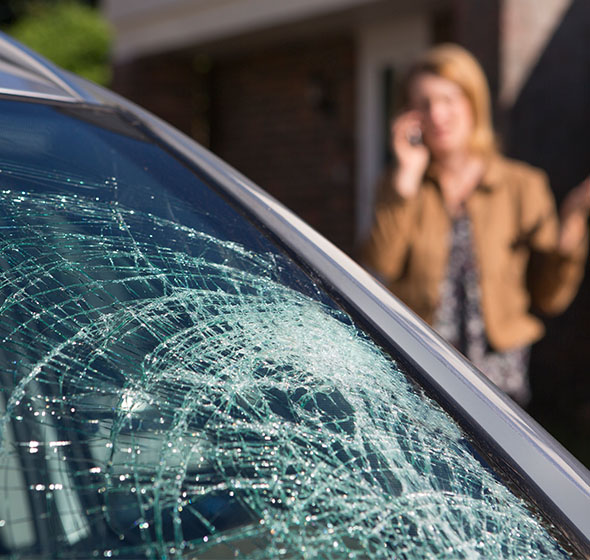 A woman on the phone next to a severely cracked widnshield